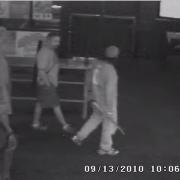 Two people walking in a dark area.