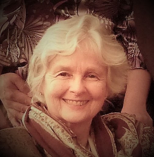 Smiling woman with white hair and scarf.
