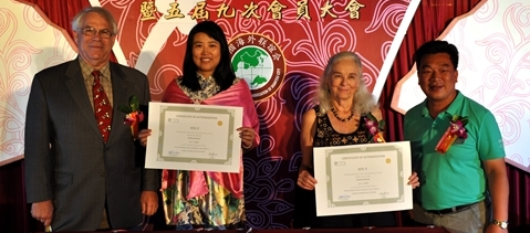 Four people holding certificates at event.