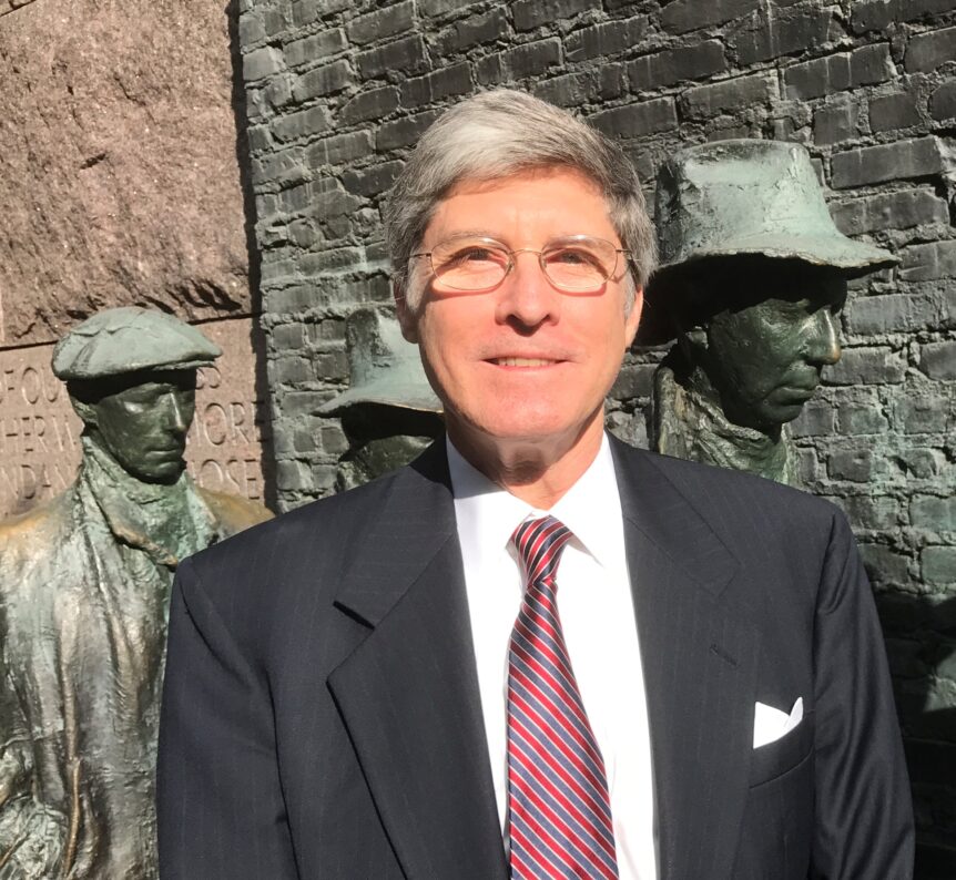 Man in suit standing by bronze statues.